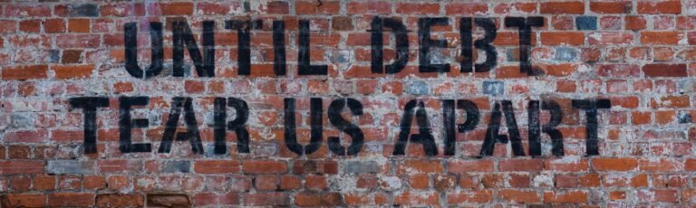 A brick wall saying 'until debt tears us apart'