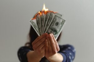 A woman is holding burning 100$ bills